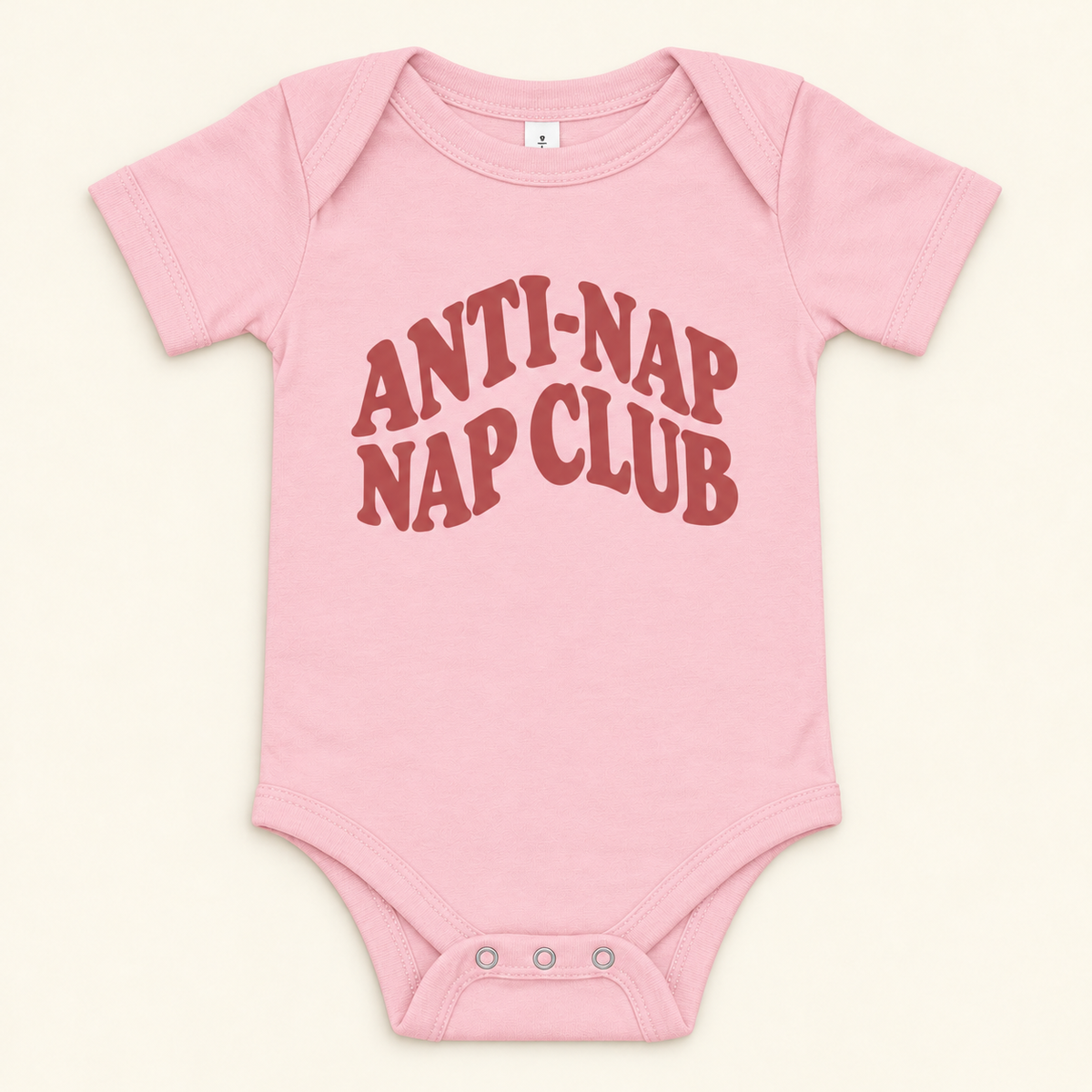 Pink baby bodysuit with dusty red Anti-Nap Nap Club lettering, front view