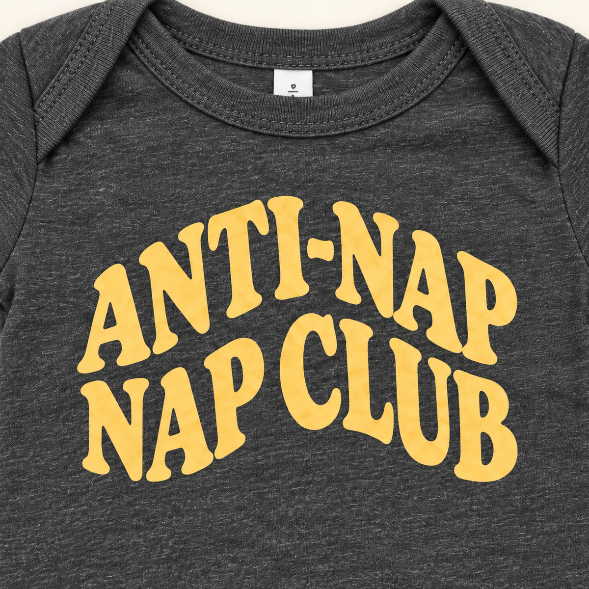 Close-up of yellow Anti-Nap Nap Club lettering on Dark Grey Heather fabric