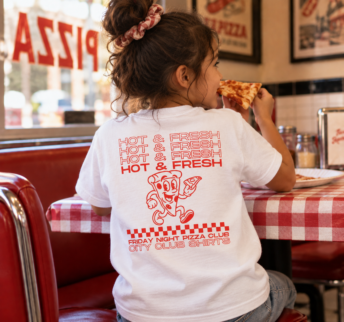 Girl wearing Friday Night Pizza Club white kids tee in a pizzeria