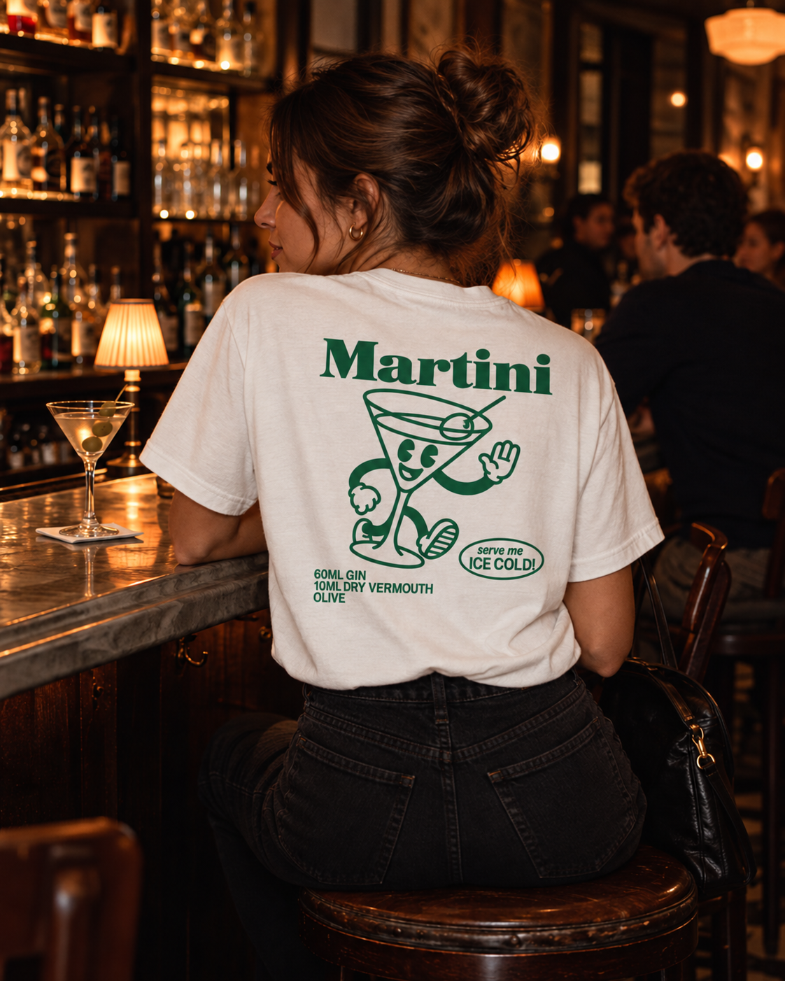 Woman wearing Martini Recipe graphic tee at a cocktail bar